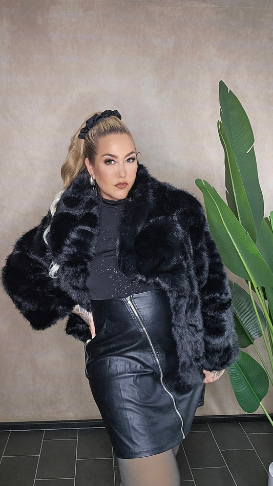 Schwarze Fake Fur Jacke Plus Size - Ganzkörperansicht mit Leder-Rock kombiniert, zeigt perfekten Sitz für große Größen