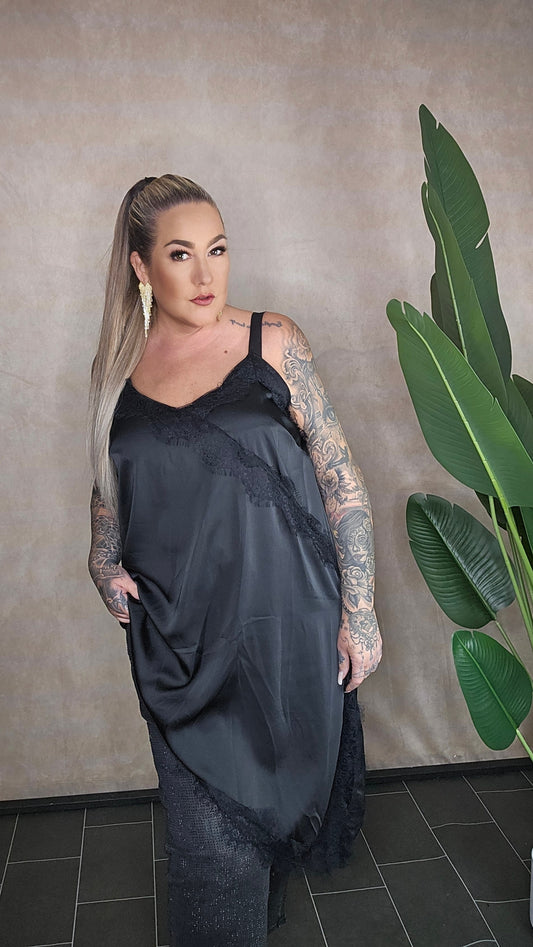 Frau in schwarzem Satin-Spitzen-Top mit Statement-Ohrringen - Frontansicht